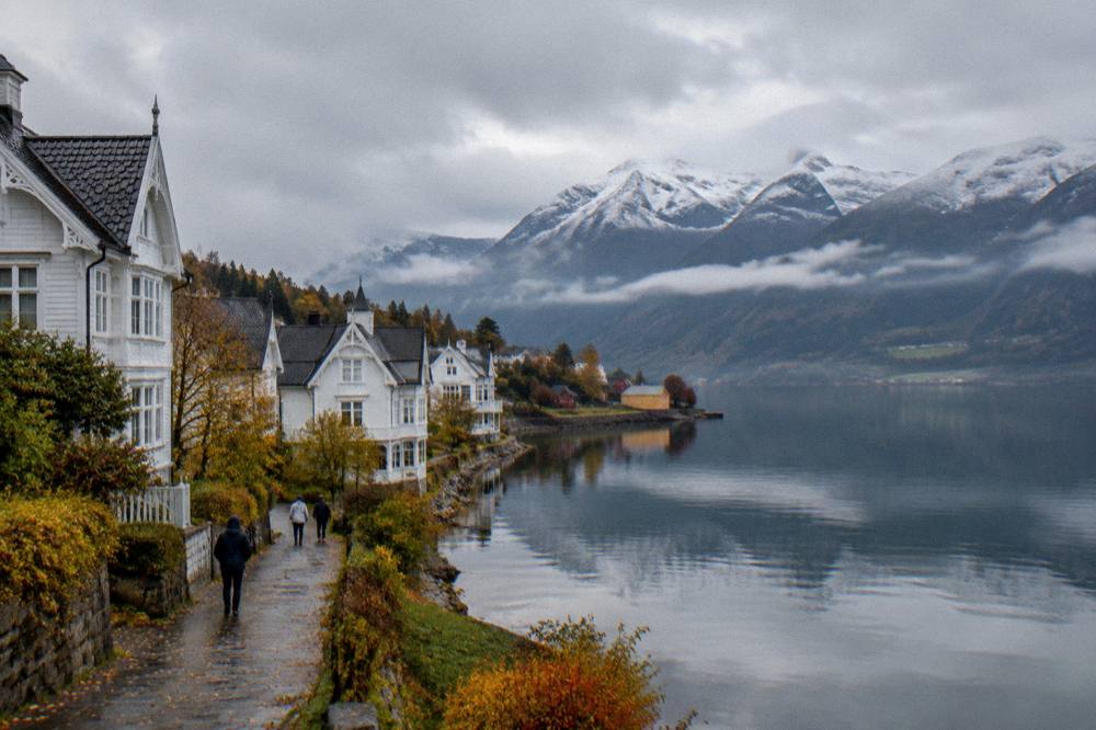 Fjord water in low autumn light with mist on the mountains and a few coloured houses at the shoreline