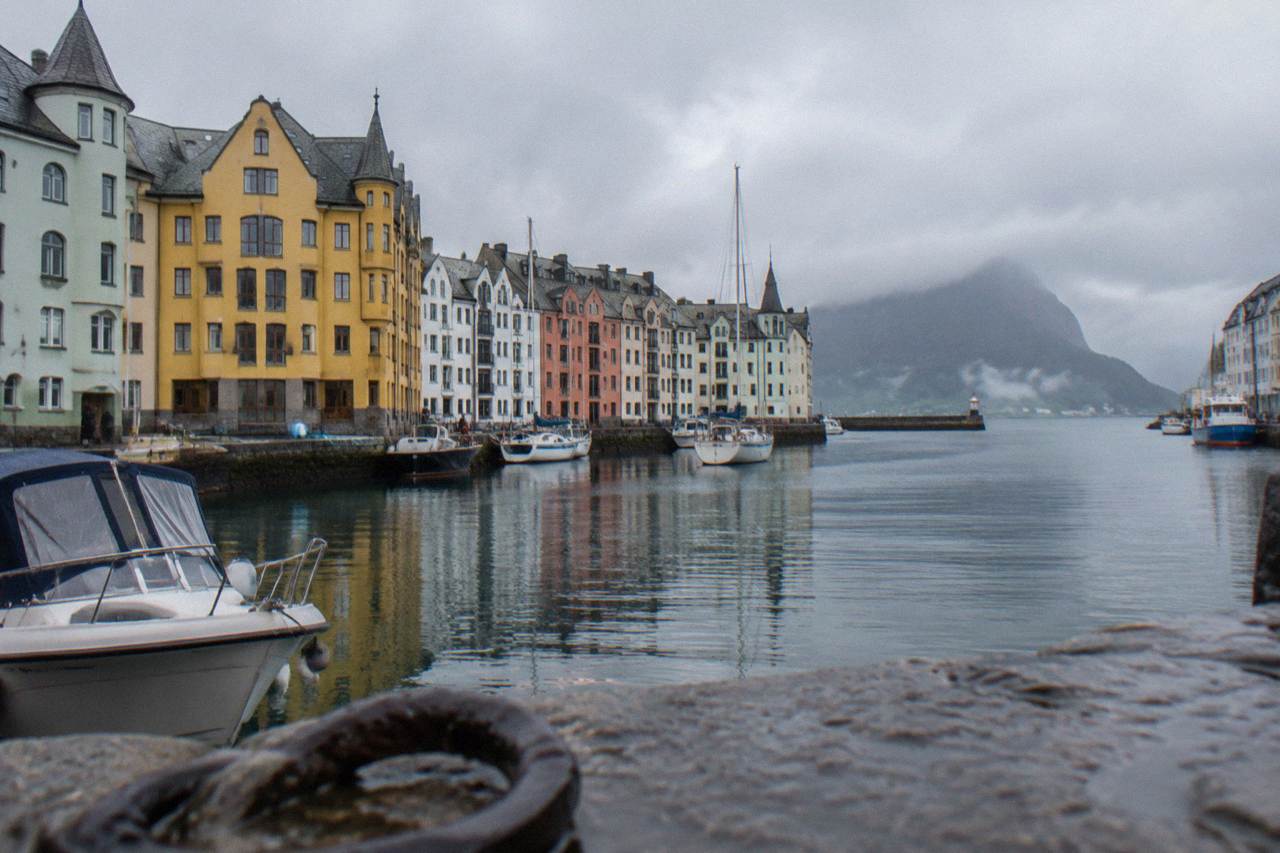 Colorful Art Nouveau buildings on a waterfront with mountains and a harbor in the background