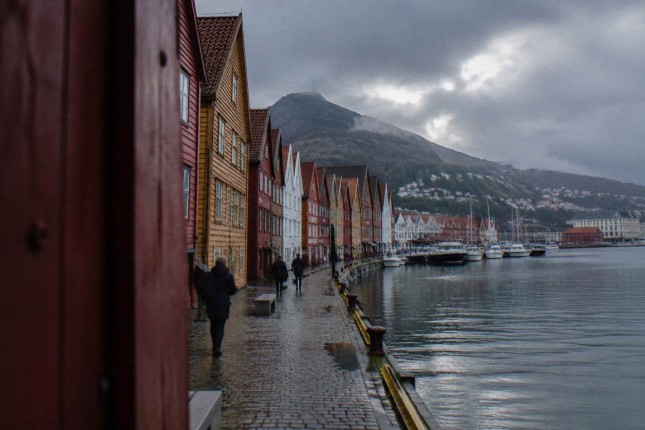Colourful wooden warehouses along the historic Bryggen wharf in Bergen, with the harbour and hills behind them