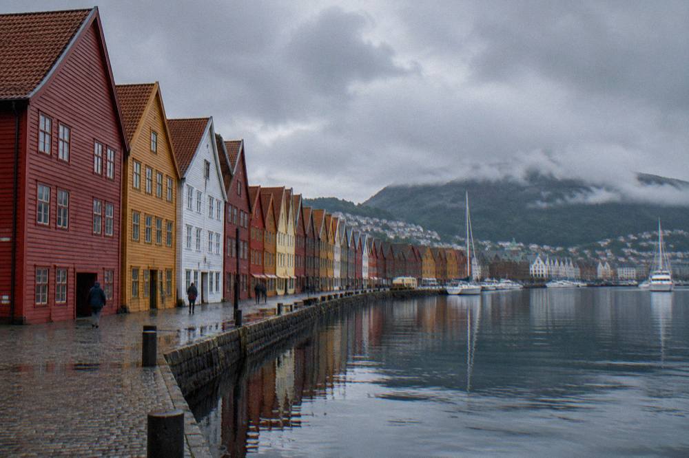 The colourful wooden wharf buildings of Bryggen in Bergen reflected in the harbour water on an overcast day