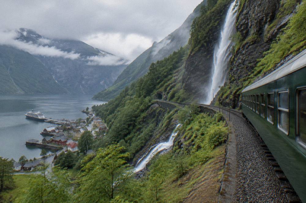 A small fjord village with wooden buildings and a cruise boat at the dock