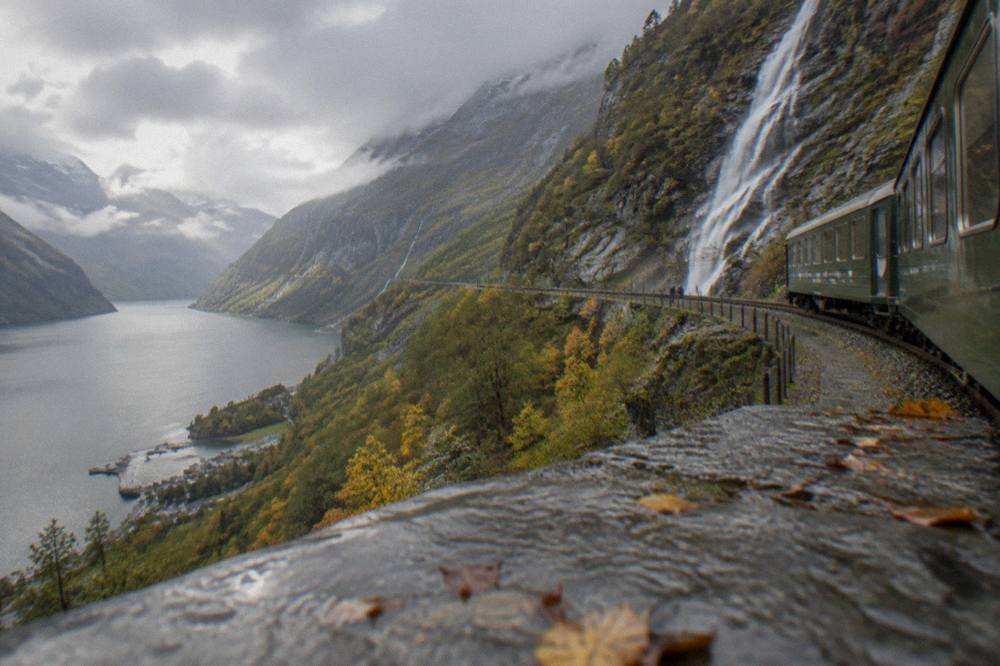 A green fjord valley in autumn with a train line visible on the far slope