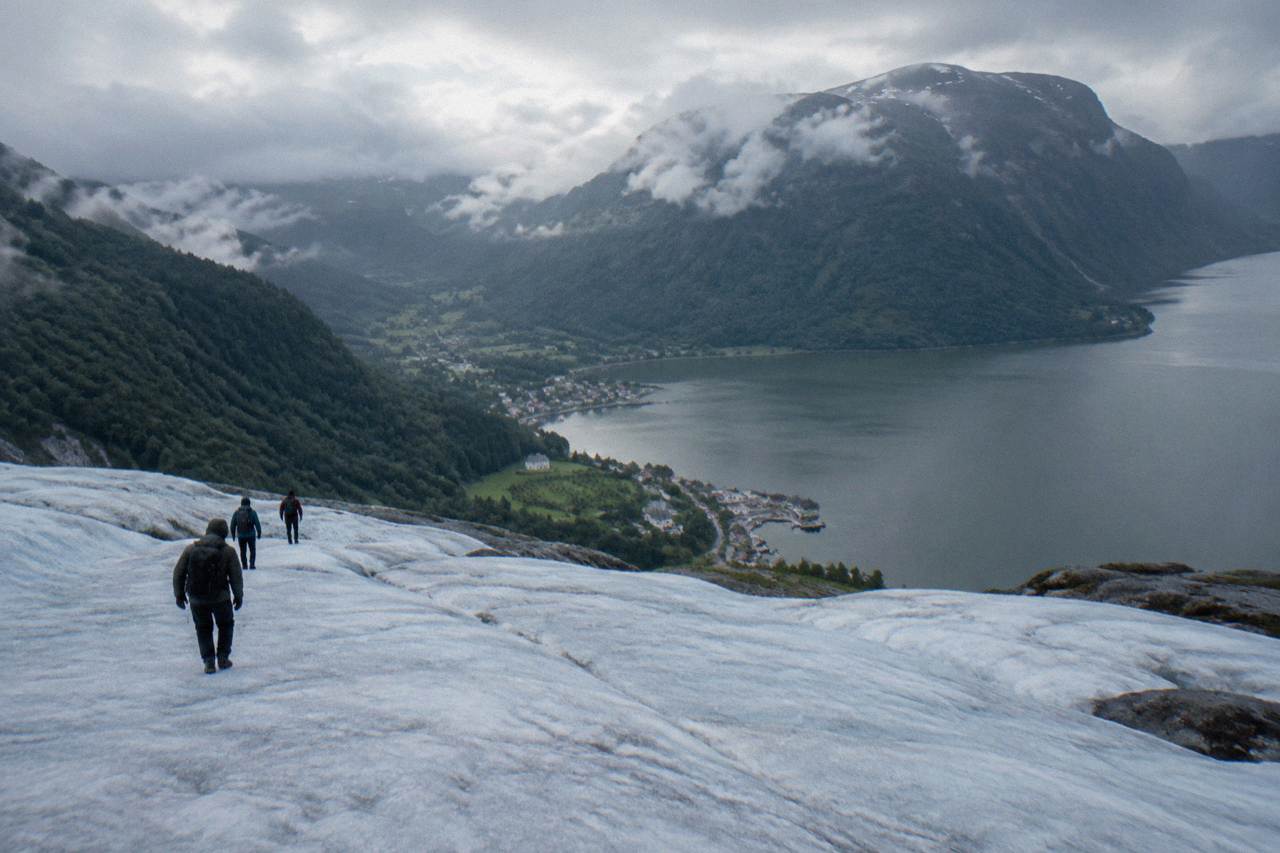 A small Norwegian village of wooden houses sitting at the end of a fjord with steep forested mountains rising behind it