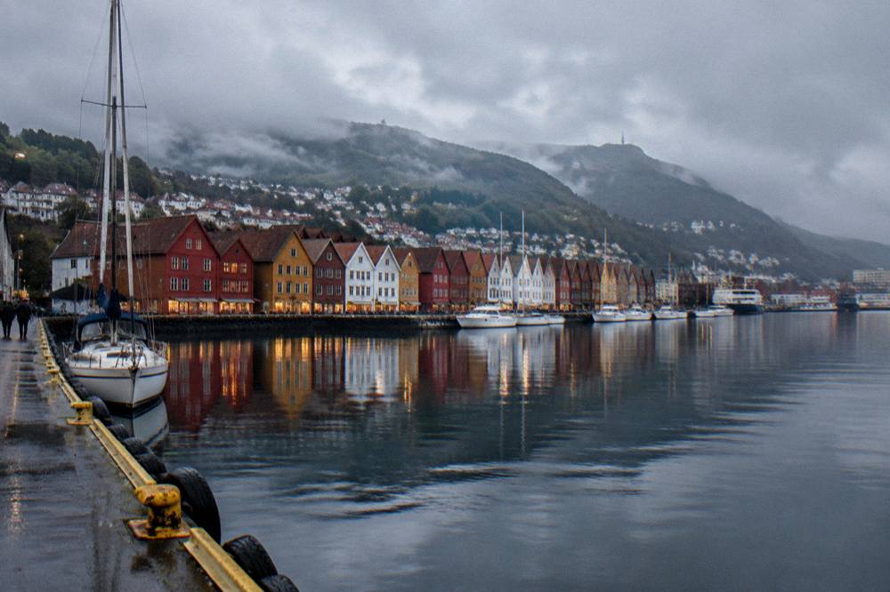 The waterfront of Bergen at dusk with colored wooden houses reflected in the still water of the harbor