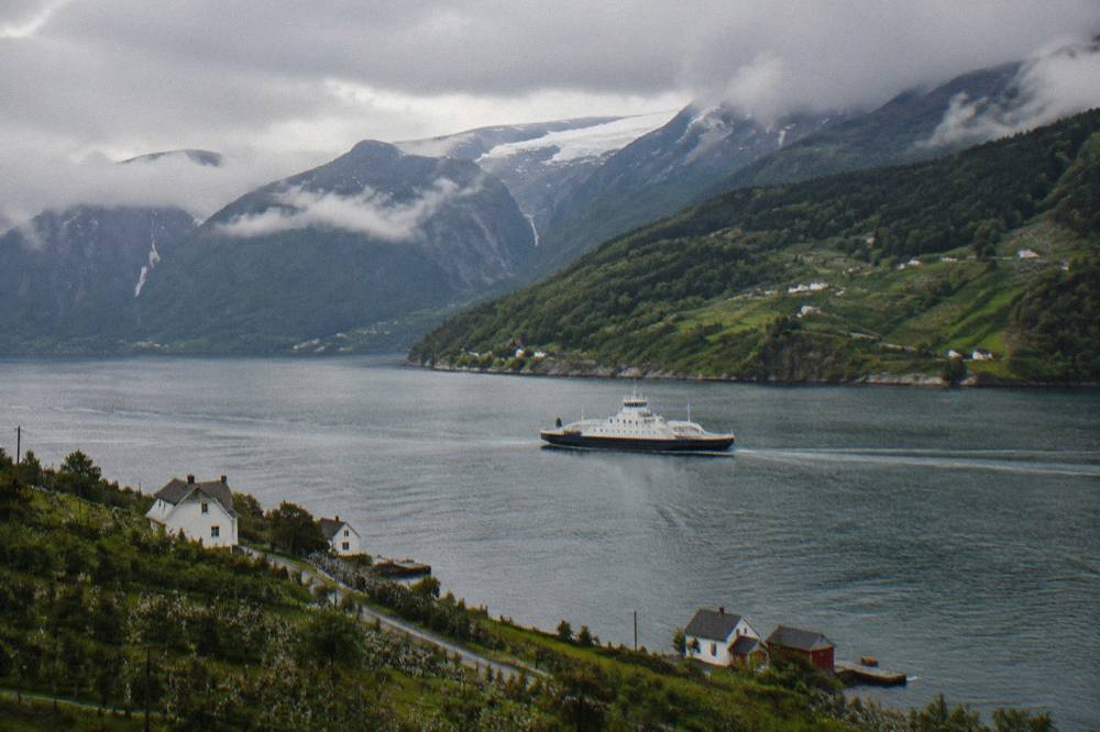 A ferry crossing the Hardangerfjord with forested hills on both shores