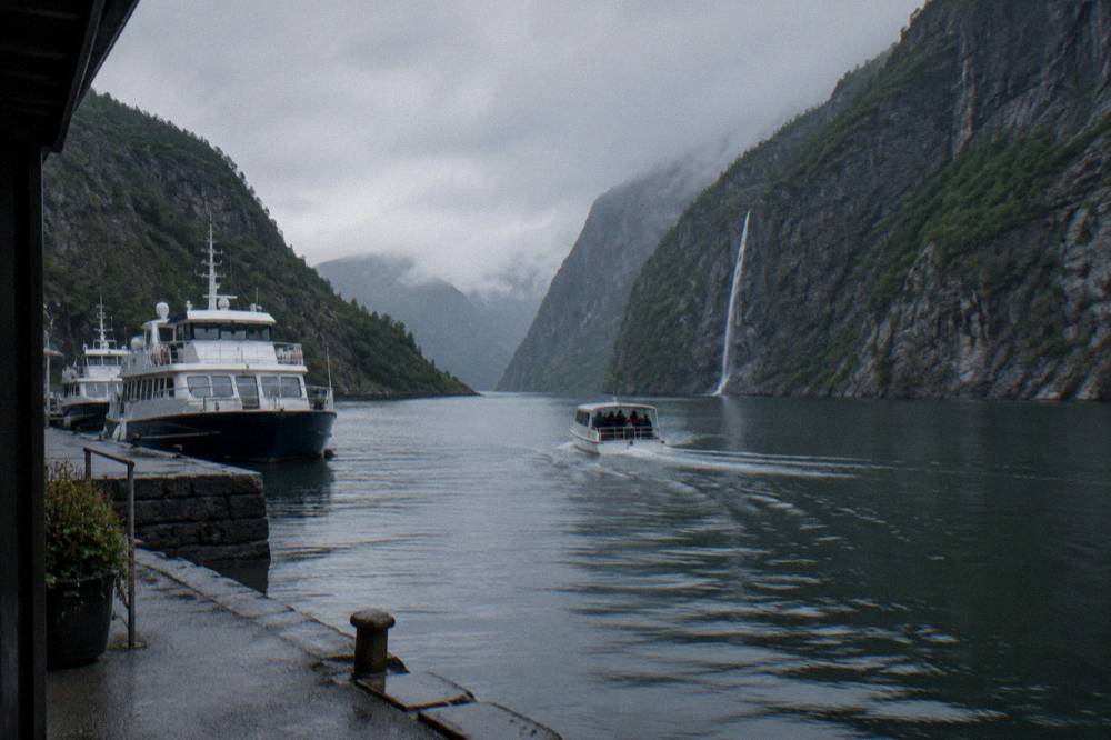 Fjord cruise boats moored along a stone quay in a Scandinavian harbour on an overcast morning