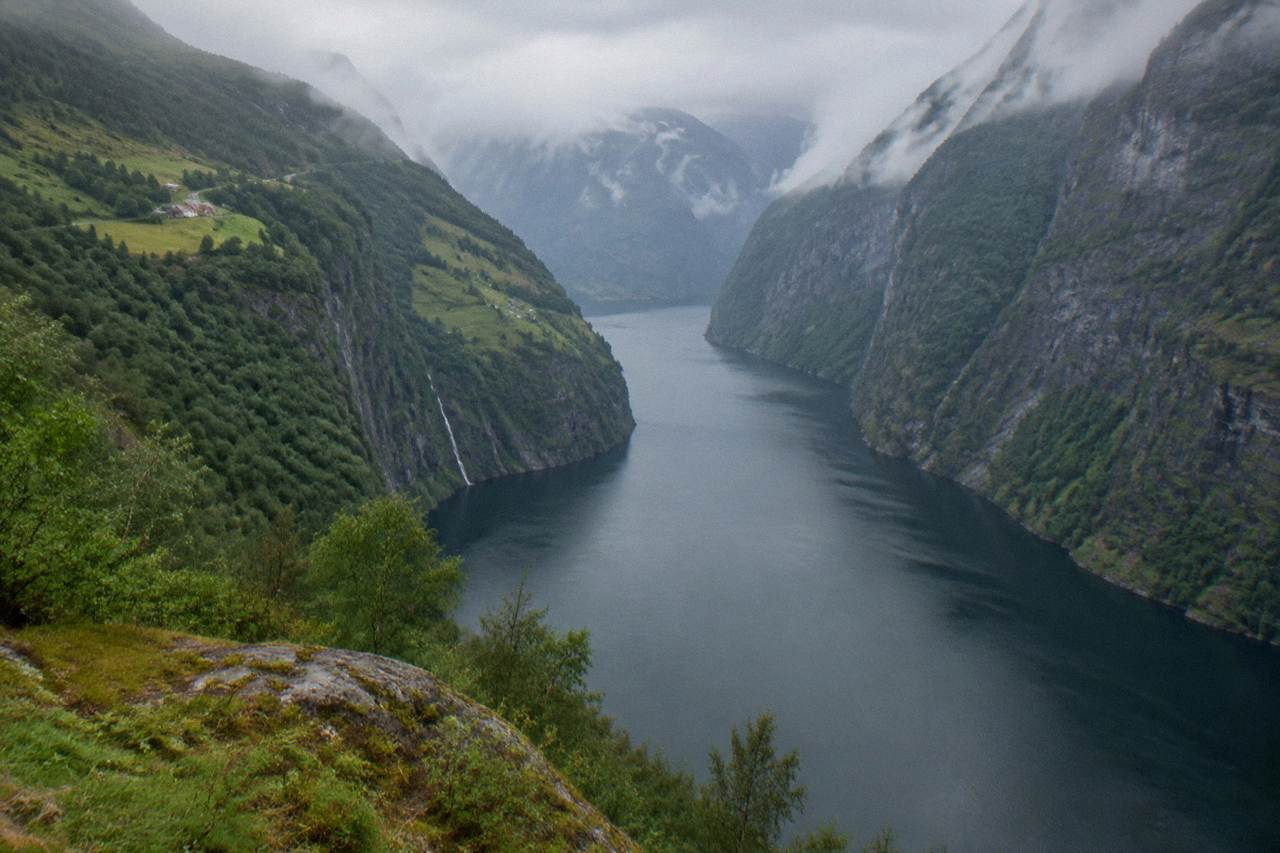 A narrow fjord with steep green cliffsides and calm dark water between them