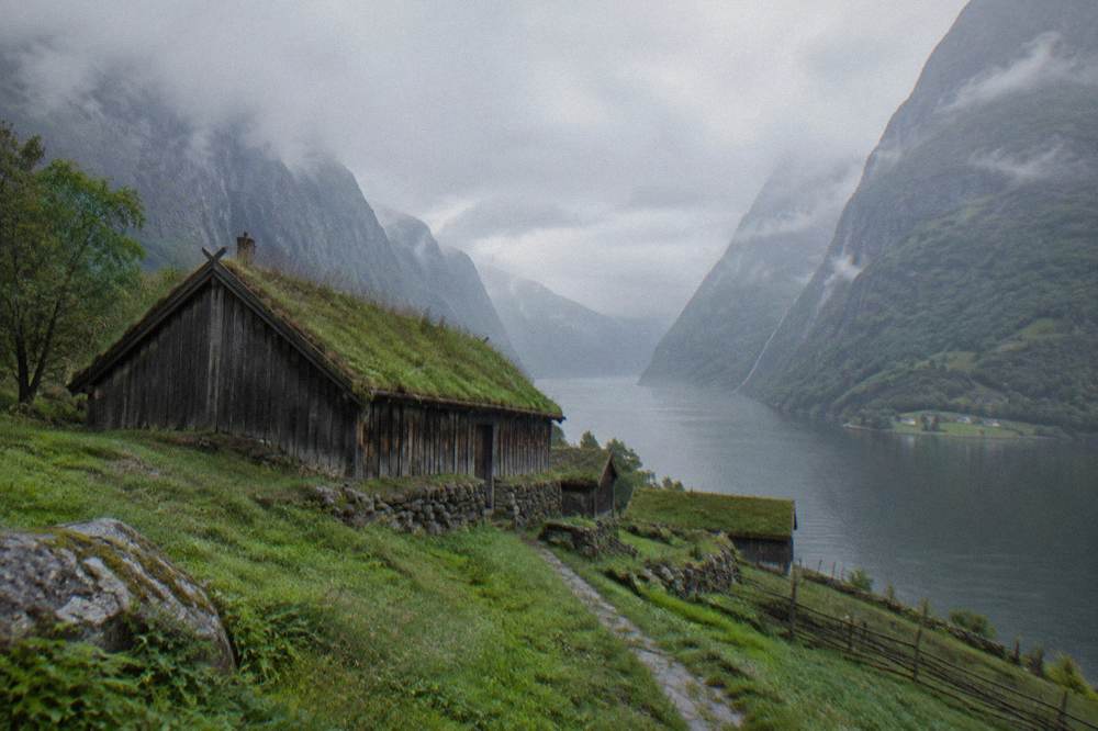 A wooden Viking longhouse with turf roofs in a green valley