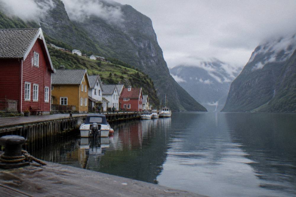 Colourful wooden houses along an old wharf with mountain slopes behind a city