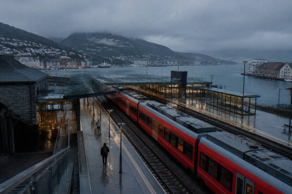 Bergen railway station platform with a red train waiting under a grey morning sky