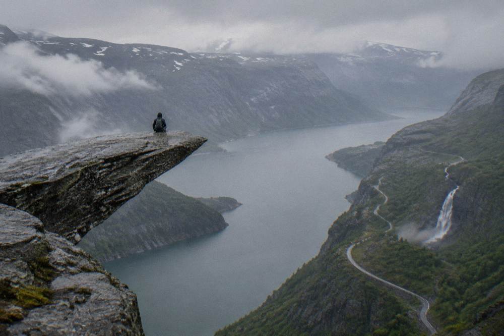 A mountain road winding up the valley toward the Trolltunga trailhead with a waterfall on the cliff