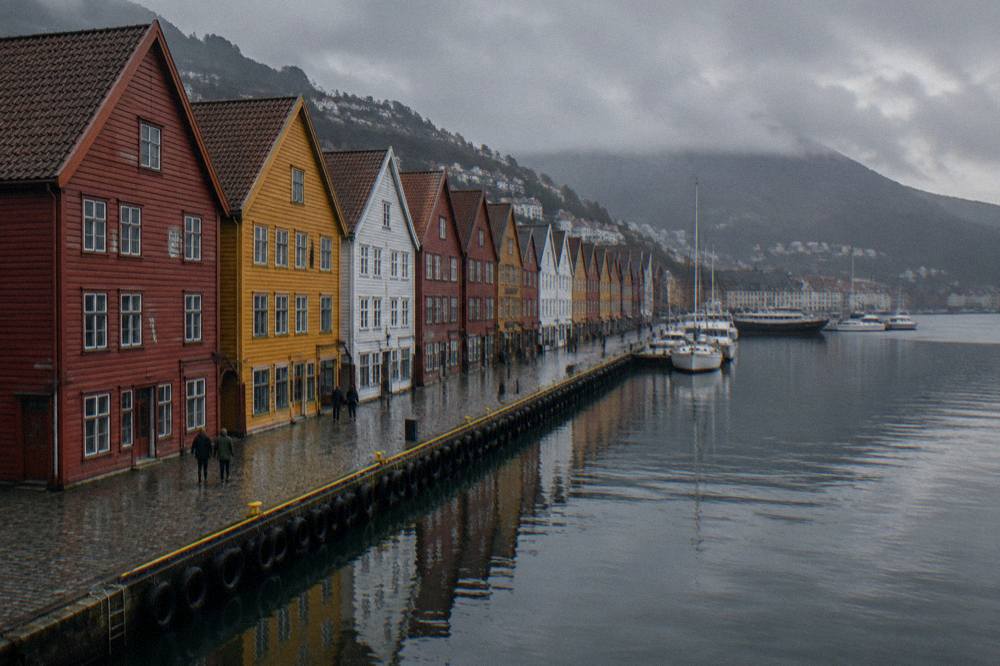 Colourful wooden houses on the Bryggen wharf in Bergen reflected in wet harbour water