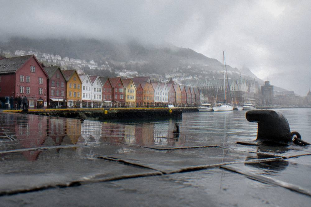 Rain clouds over the Bergen harbour with colourful wooden buildings reflected in wet pavement