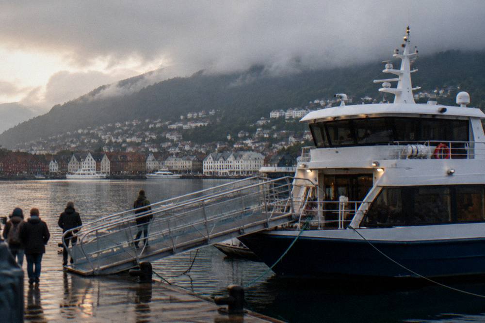 A sightseeing boat moored at a Bergen dock with a wide boarding gangway leading on board