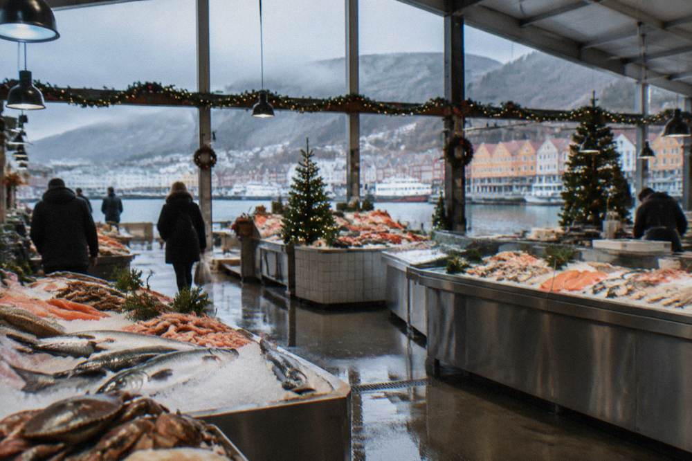 An indoor fish market hall with fresh seafood counters and Christmas decorations in Bergen