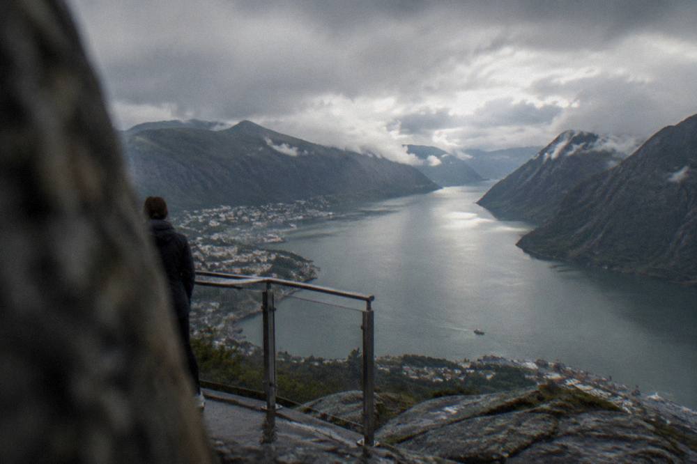 A mountain viewpoint platform overlooking a narrow fjord arm between steep cliffs
