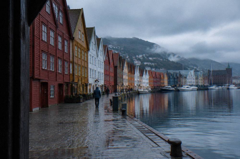 Colourful Hanseatic wooden buildings at Bryggen reflected in harbour water on an overcast day