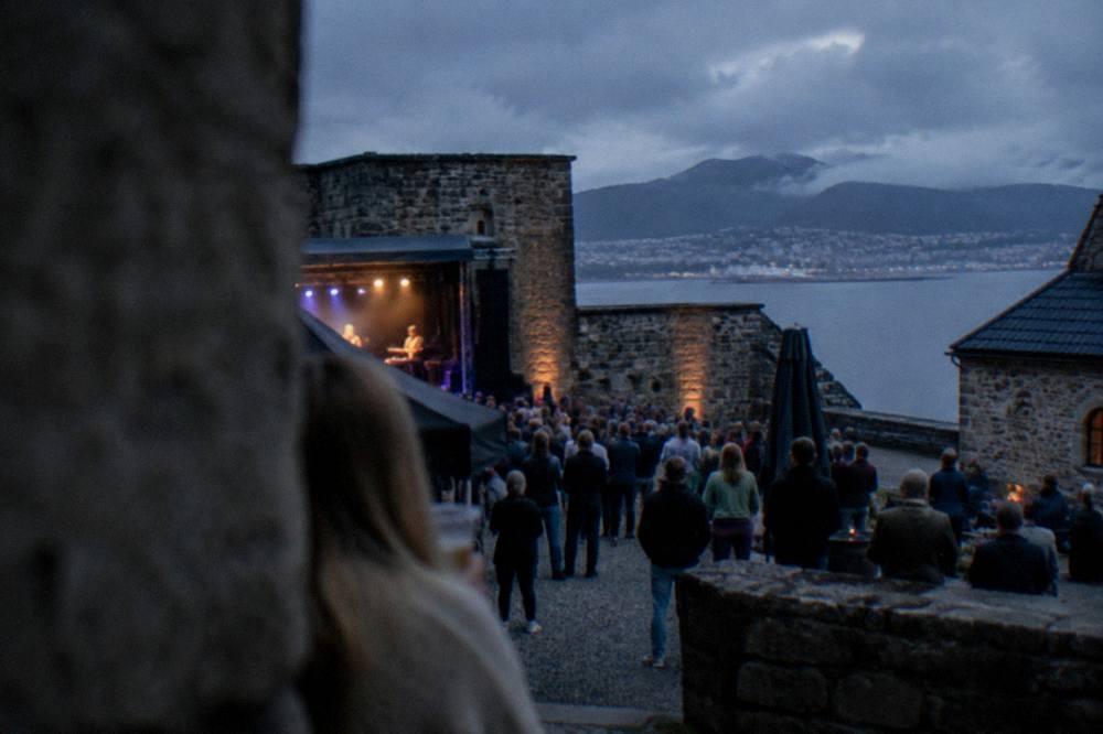 Festival crowd gathered inside a historic stone fortress courtyard in Bergen on a summer evening