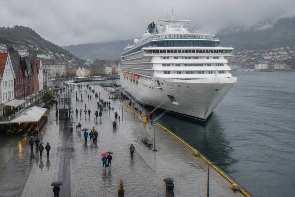 A cruise ship docked at the harbour in Bergen, Norway, with people walking along the waterfront promenade
