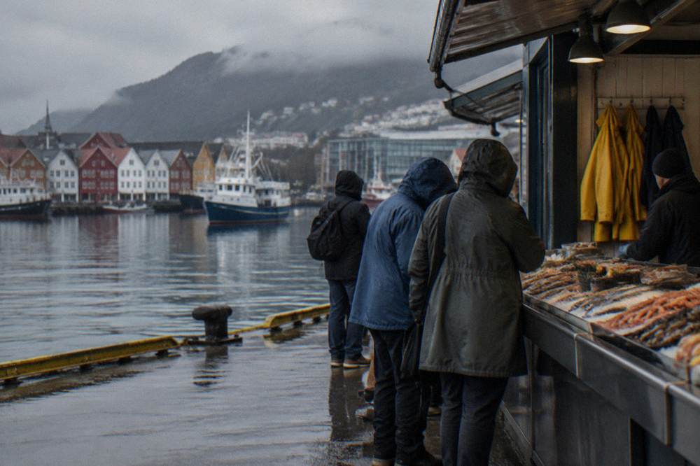 Visitors sampling dishes at a seafood counter with rain jackets hanging by the door