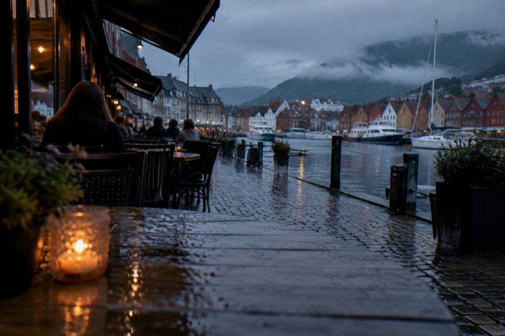 A narrow café-lined street in central Bergen with people seated at outdoor tables