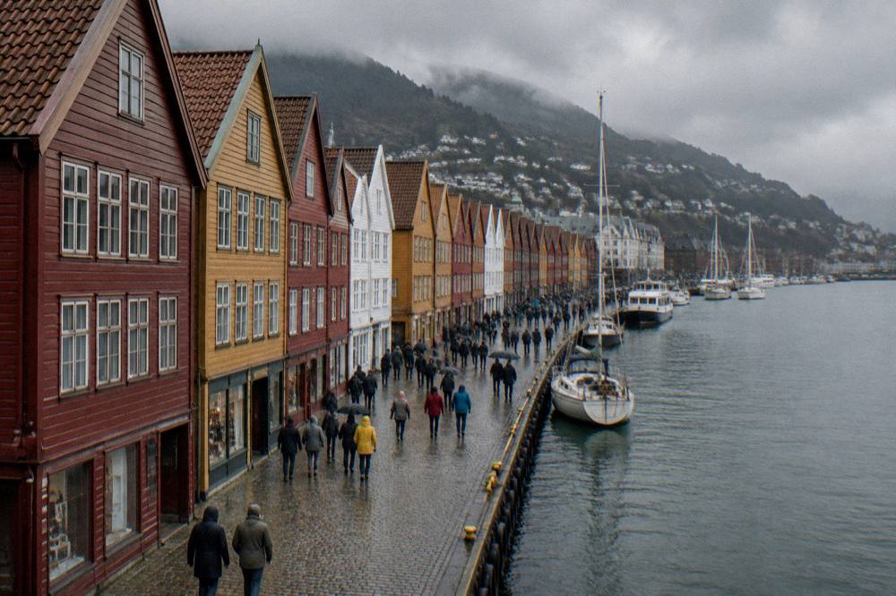 Tourists walking along the row of colourful Hanseatic warehouse facades at Bryggen