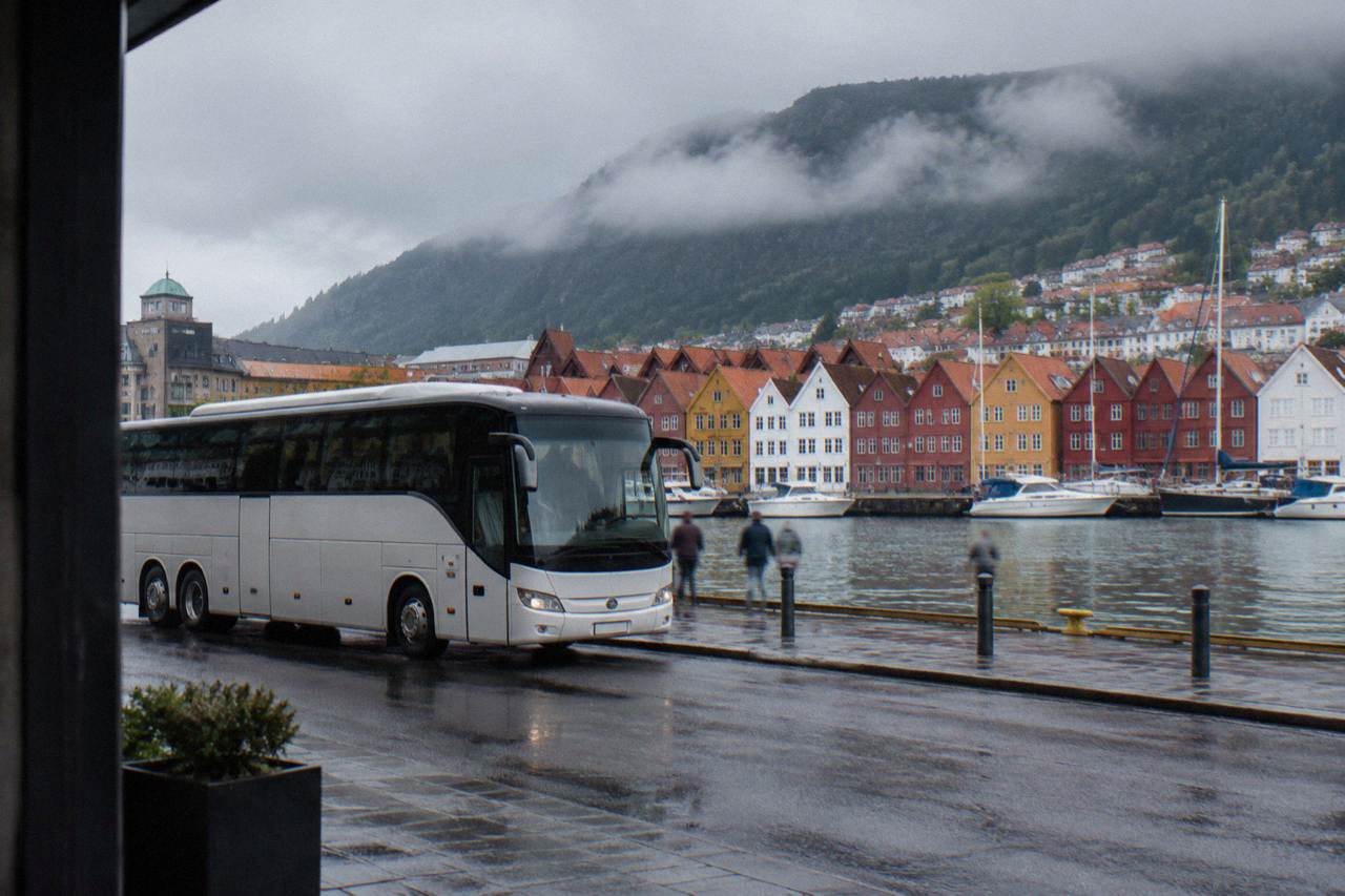 A sightseeing bus parked on a quay street with colourful wooden Hanseatic buildings along the waterfront behind it