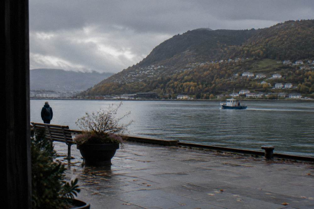 A small boat on a calm fjord with autumn colored hillsides near Bergen