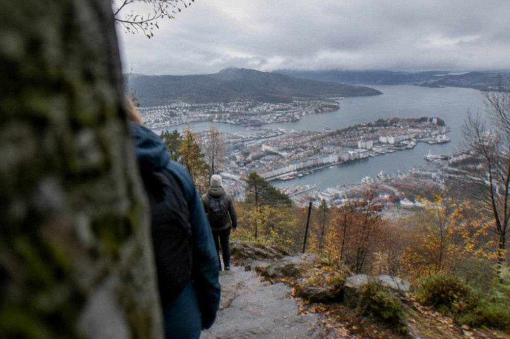 Hikers on an autumn trail above Bergen with the city and harbor below