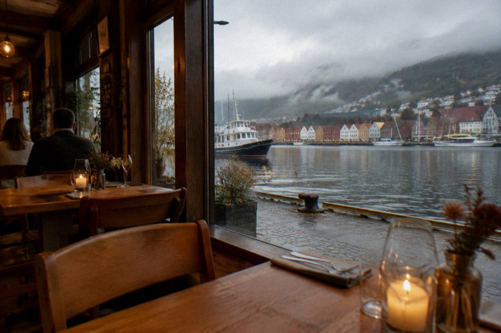 Warm light inside a Bergen restaurant with wooden tables and candles
