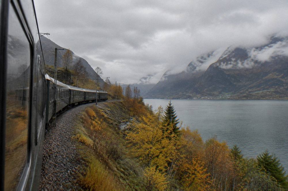 A passenger train crossing a mountain plateau with autumn colors between Oslo and Bergen