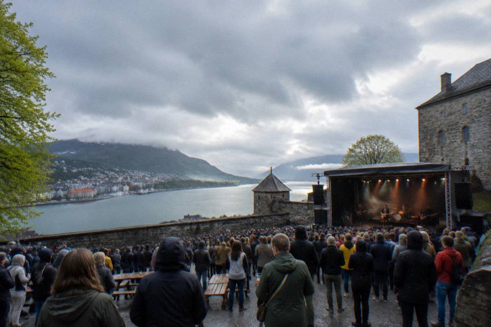 An outdoor concert crowd gathered at a fortress courtyard in Bergen during an evening festival