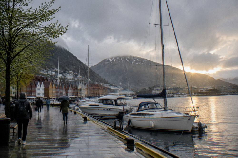 The harbor in Bergen at sunset with moored boats and mountains in soft spring light