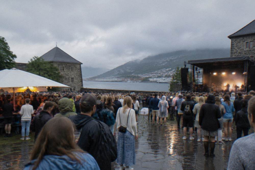 Festival crowd gathered inside the stone walls of Bergenhus Fortress on a light June evening in Bergen