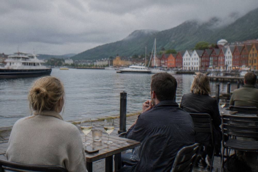 People sitting outdoors at quayside tables in Bergen enjoying a long bright summer evening