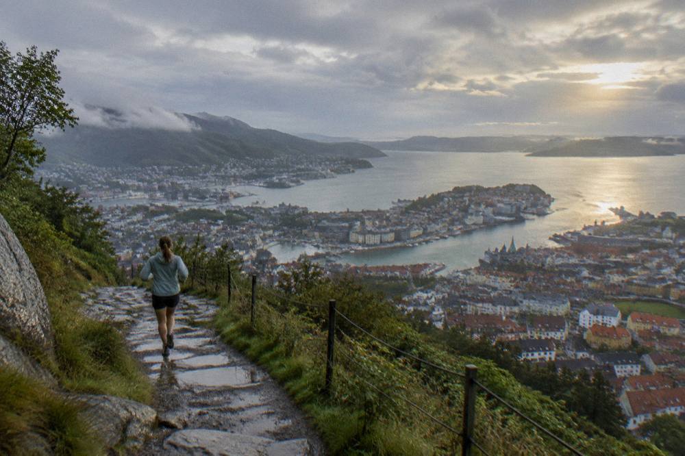 View from a mountain terrace above Bergen across the city rooftops to the fjord and islands in warm evening light