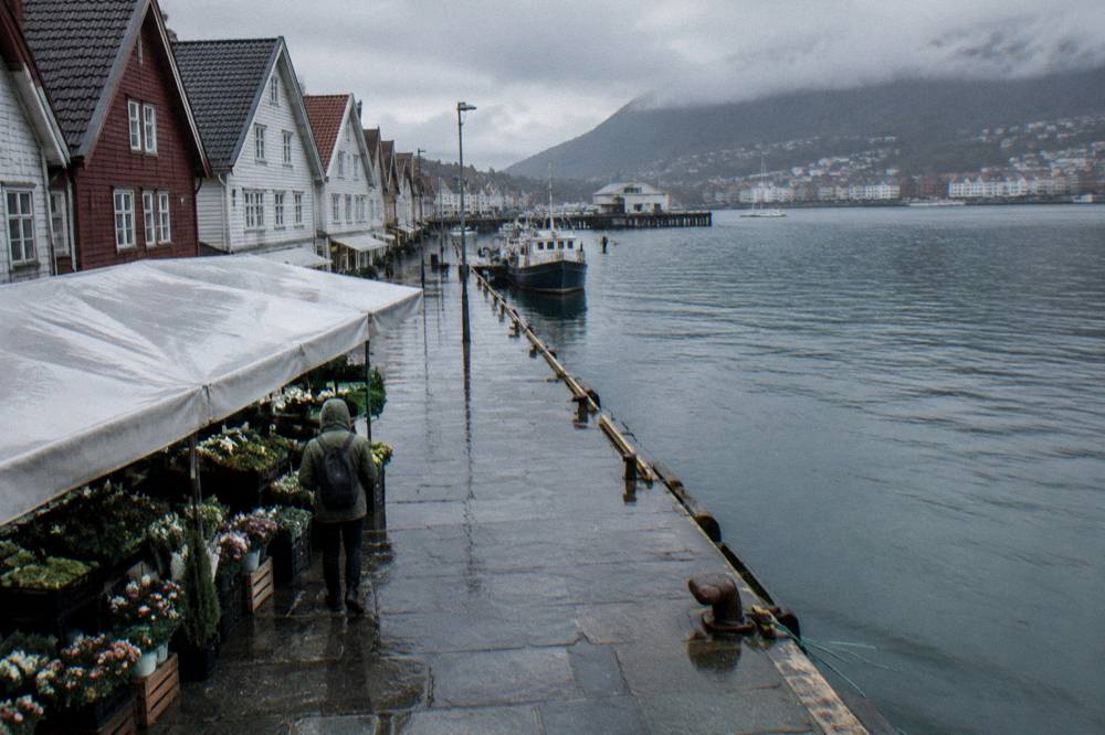 Person in a rain jacket browsing exhibits inside a warmly lit Norwegian museum gallery