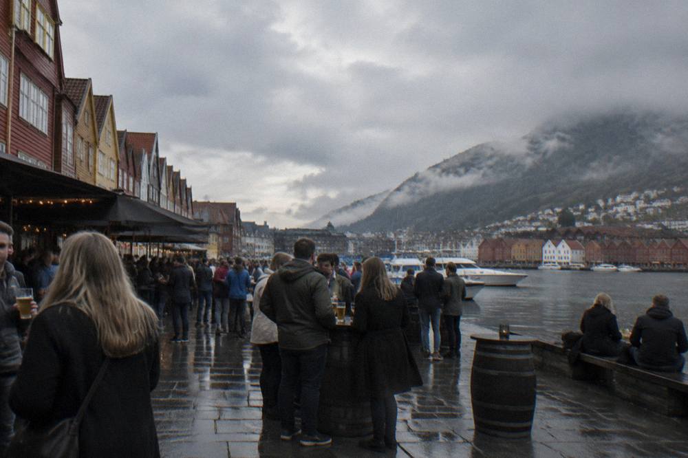 Crowded bar street with people holding drinks in central Bergen