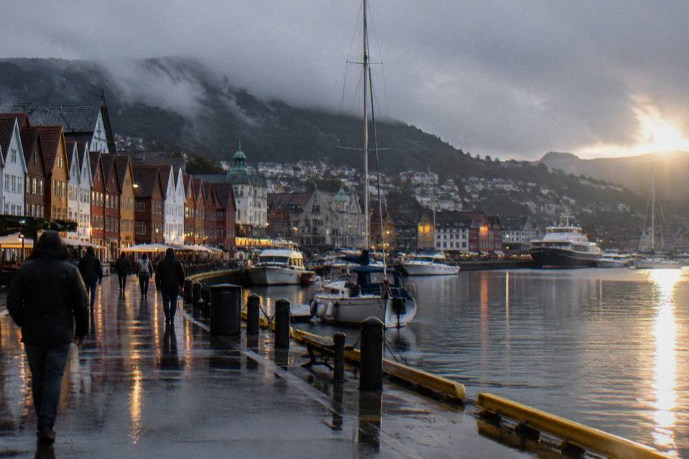 Harbour promenade at dusk with moored boats and city lights