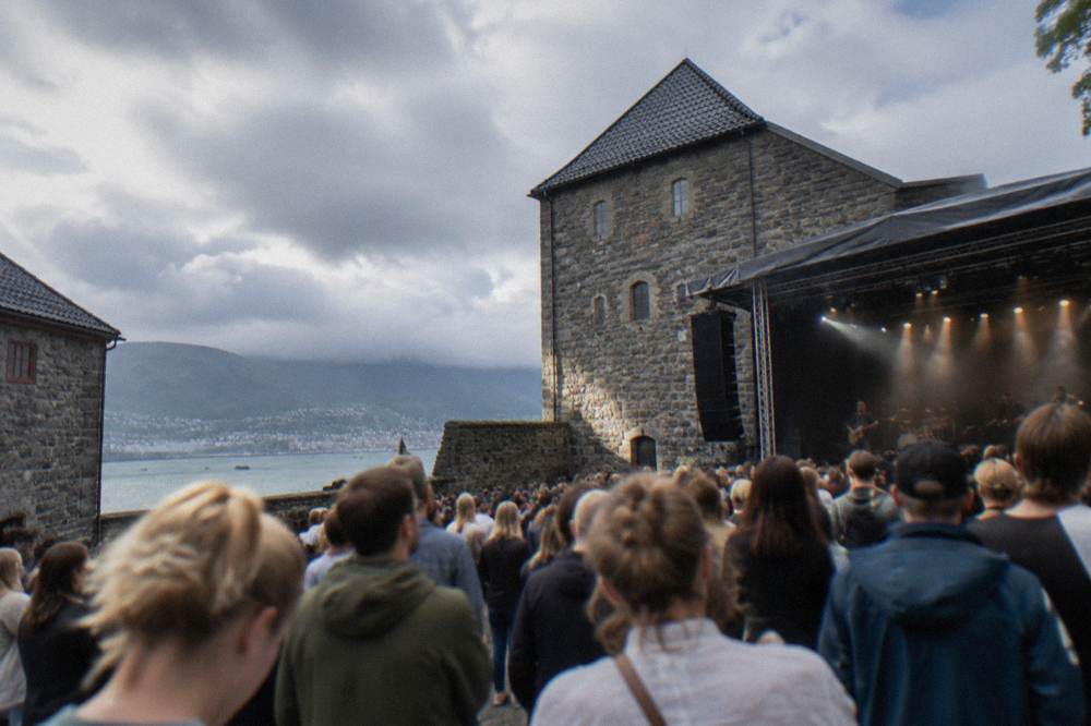 Concert crowd gathered in a stone fortress courtyard at a summer festival