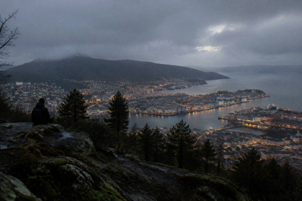 Night view over lit rooftops of Bergen from a mountainside above the city