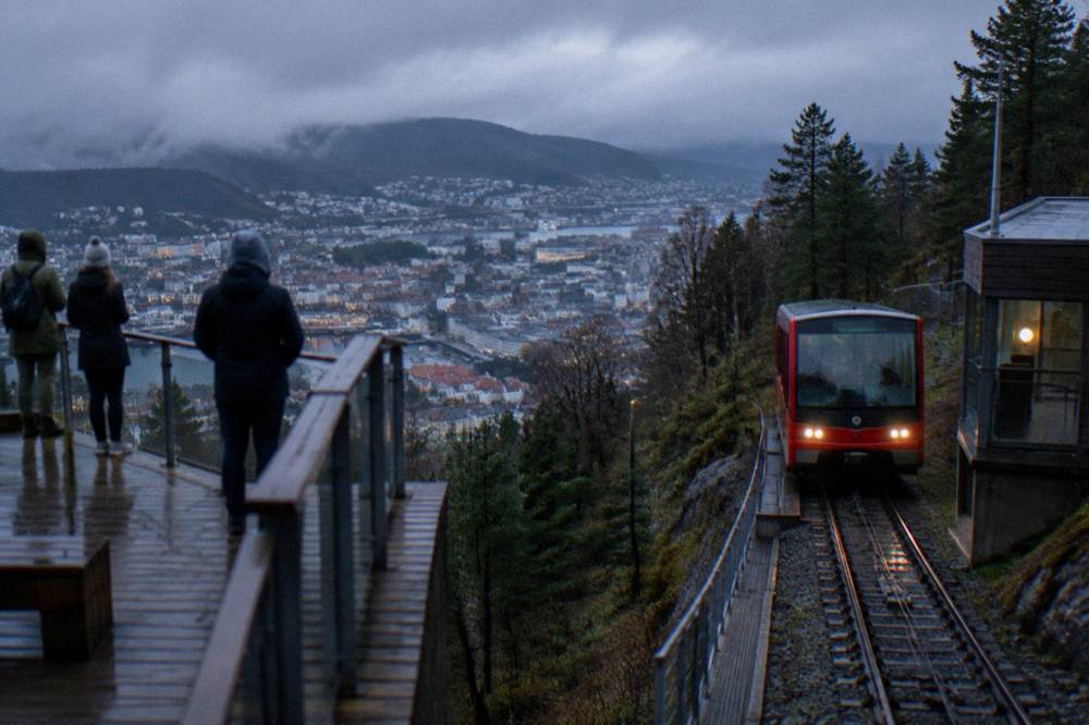 A red Fløibanen funicular carriage arriving at a mountain station above Bergen