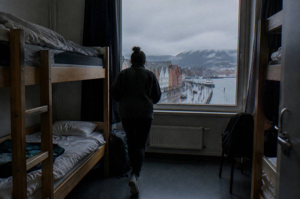 A simple hostel dormitory room with bunk beds and a window overlooking a Norwegian street