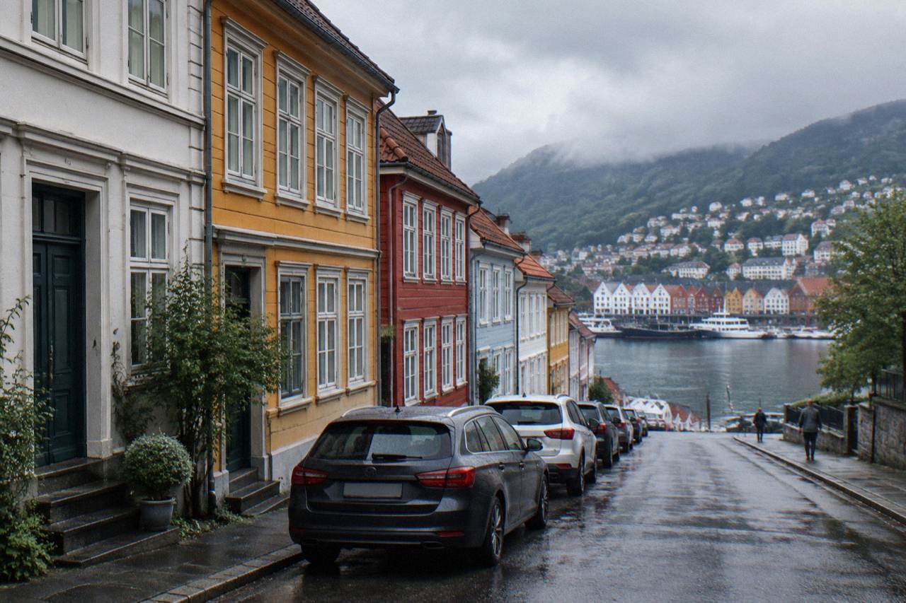A quiet street in central Bergen with colourful historic townhouses and parked cars along the kerb