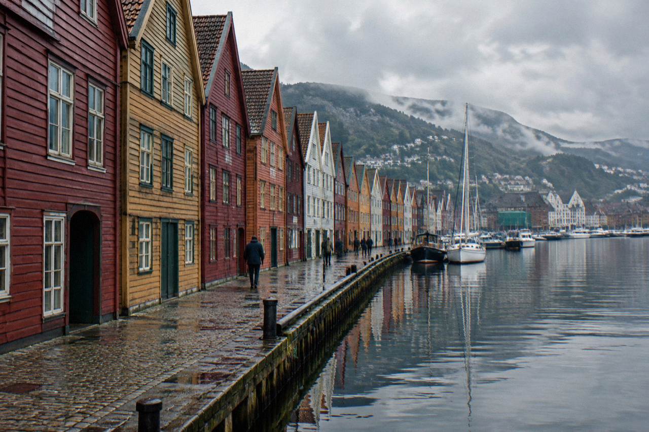 Colorful wooden warehouses of the Bryggen wharf reflecting in calm harbor water in soft evening light