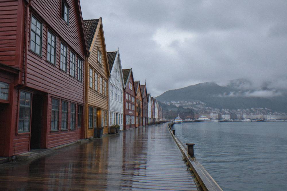 Row of narrow gabled wooden buildings along the wharf at dawn with an empty walkway