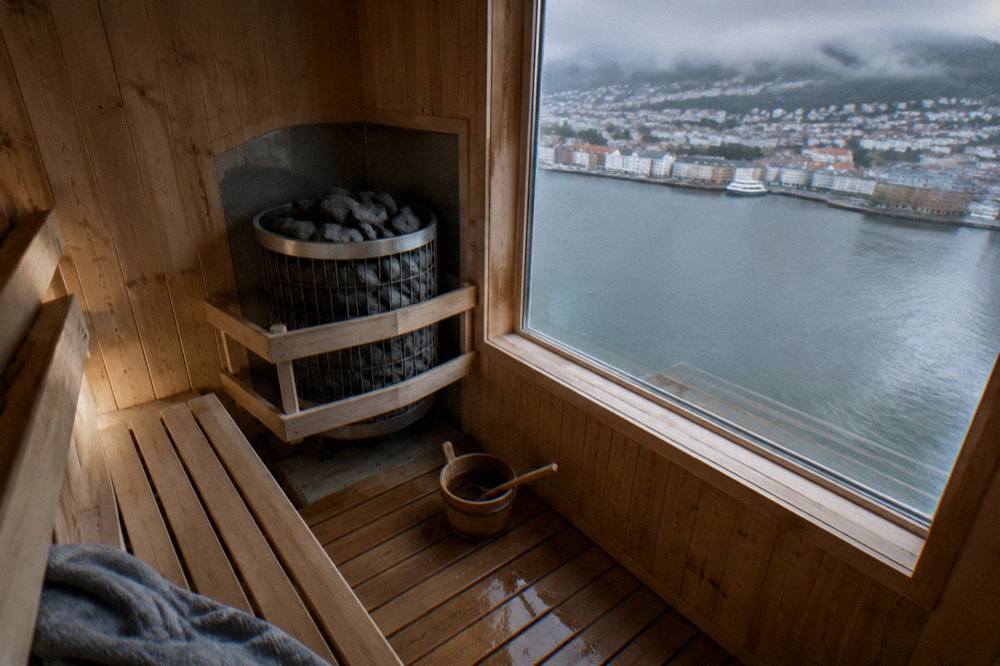 A wooden sauna interior with warm benches and a stove with heated stones