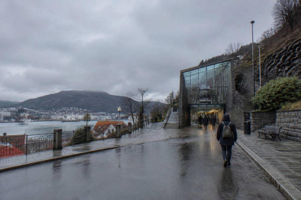 A visitor walking toward the Fløibanen funicular station in central Bergen on a damp street