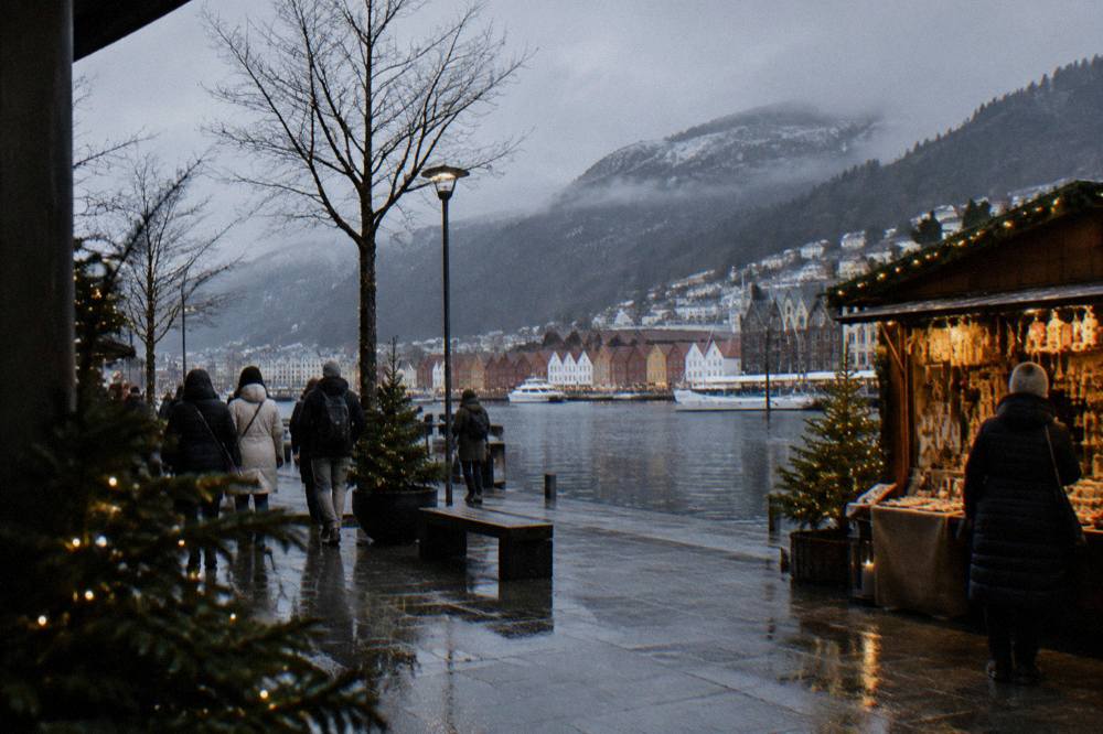 A winter street in Bergen decorated with Christmas lights and a wooden market stall