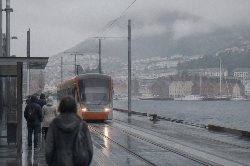 A Bybanen light rail tram arriving at a stop in central Bergen with passengers waiting
